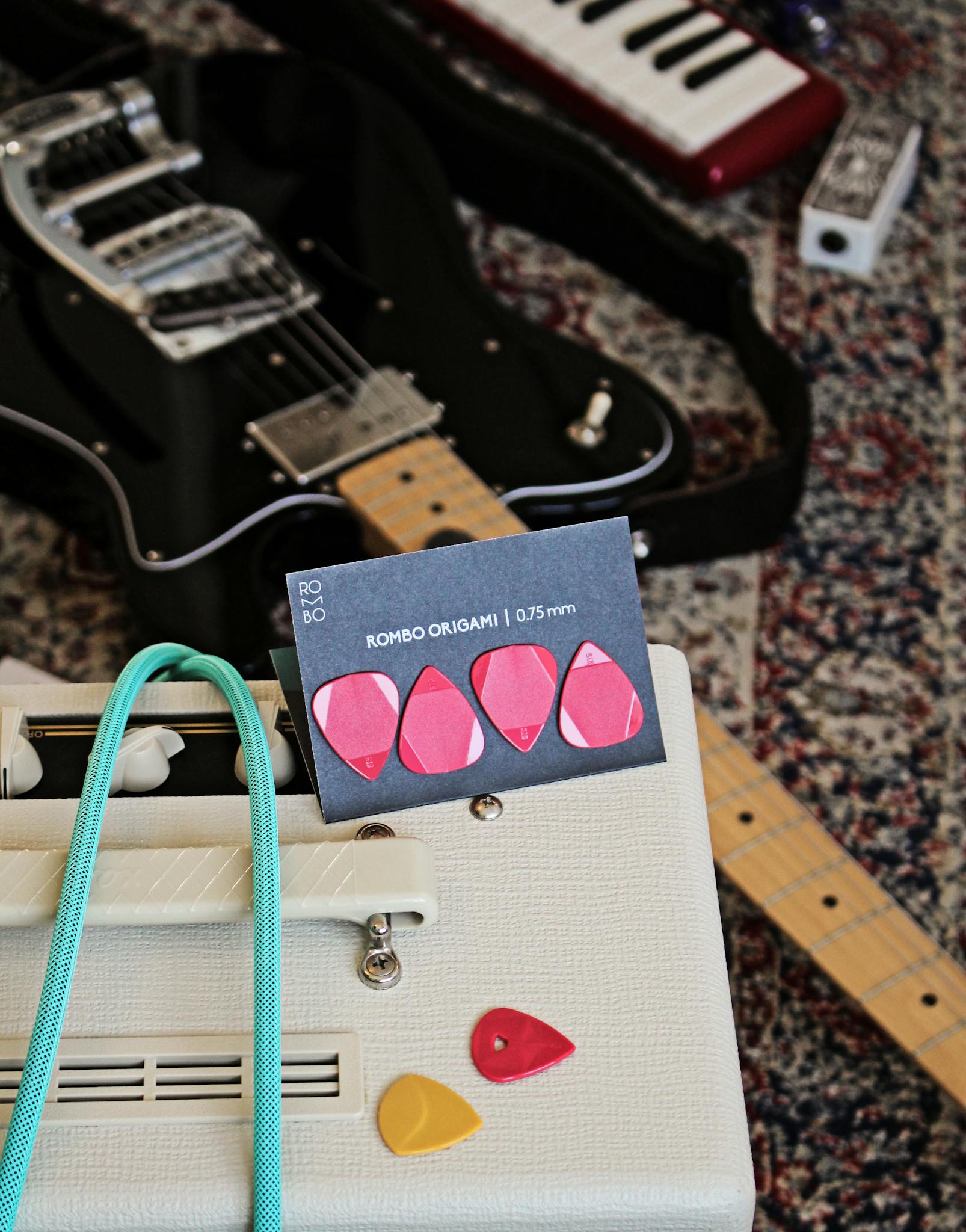 A setup featuring a guitar, amplifier, and picks on a vintage rug, perfect for musicians.
